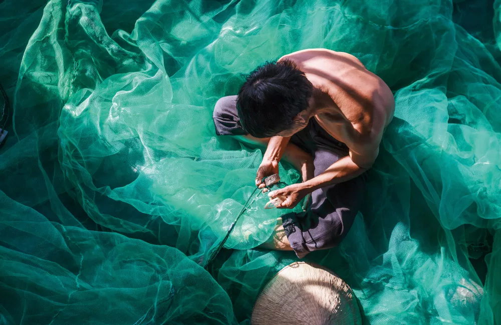 Fisherman mending fishing net